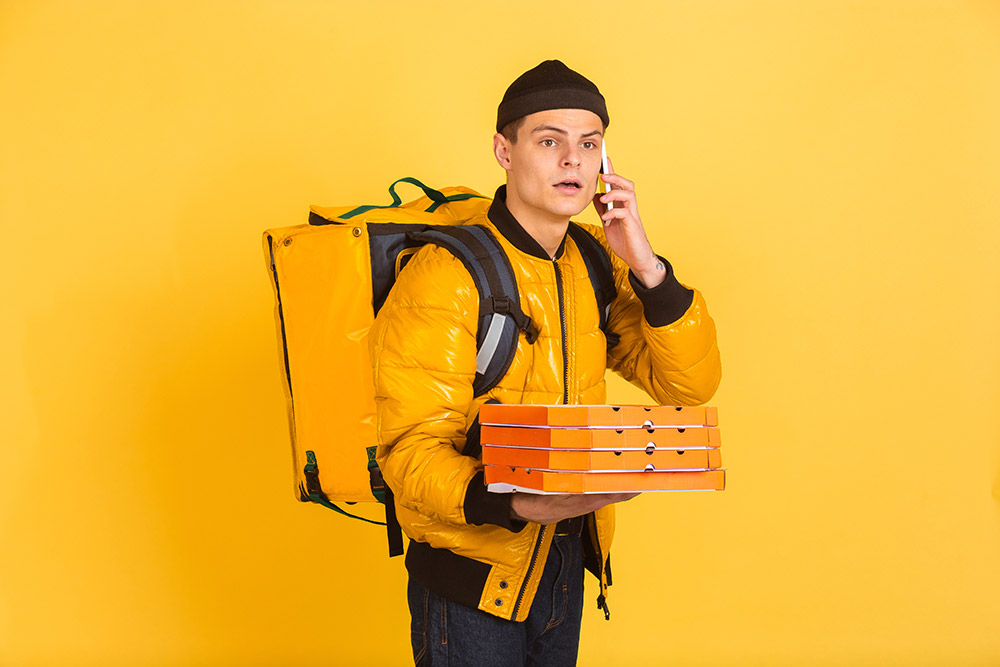 delivery service concept man delivers food and shopping bags isolated on yellow wall