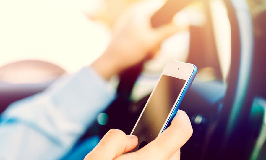 man driver holding smartphone in car